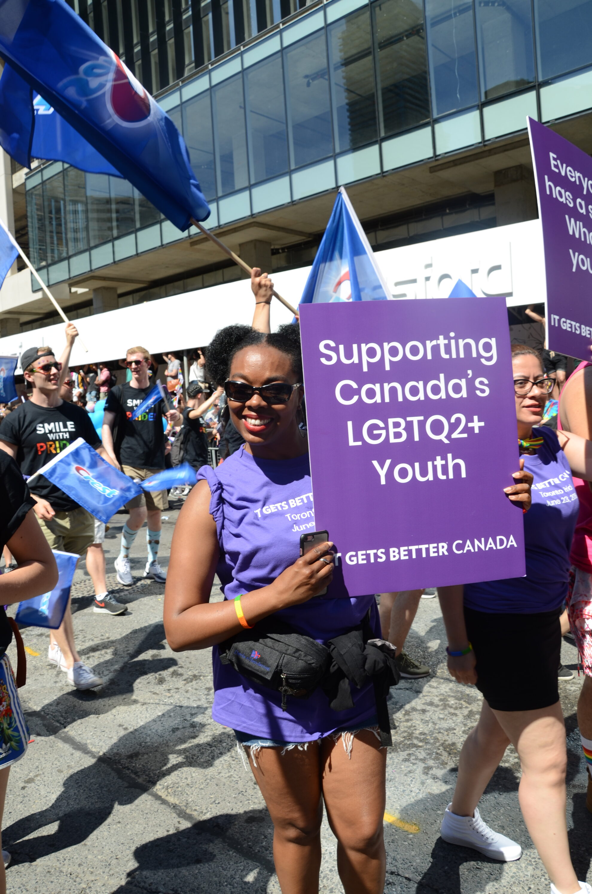 Person holding a, "Supporting Canada's LGBTQ2+ Youth. It Gets Better Canada" sign.