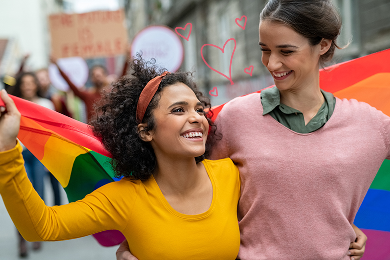 a photo of two people looking at each other holding a pride flag