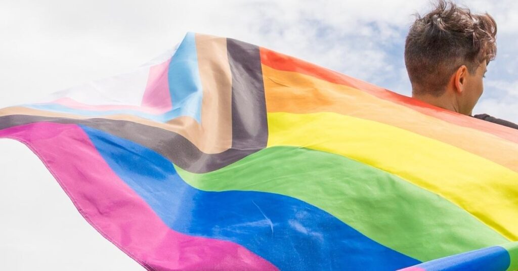 a photo of someone holding a pride flag around their shoulders