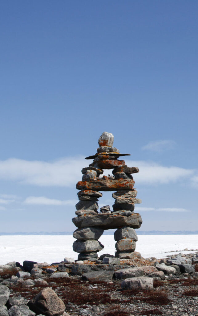 Pictured is an Inuksuk with clear blue skies and snow on the ground in Nunavut